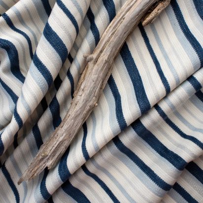 eco-friendly blue striped outdoor fabric folded rumpled with a piece of driftwood