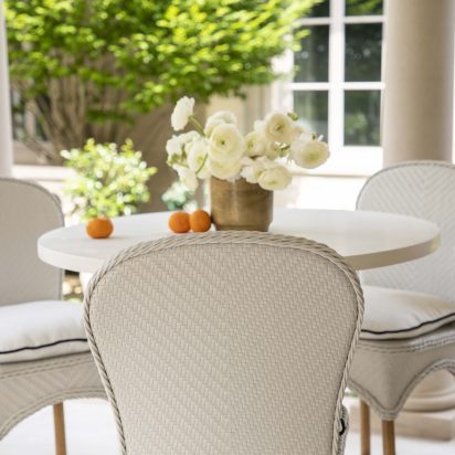 white wicker counter or bar stools with white table, cream ranunculus and oranges
